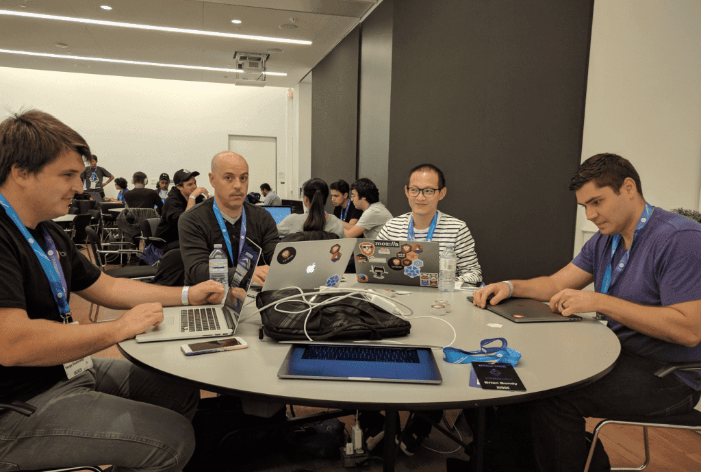 Sergey Zhukovsky, Aubrey Keus, Anthony Tseng, and Kamil Jozwiak sit at a round table with their laptops opened.